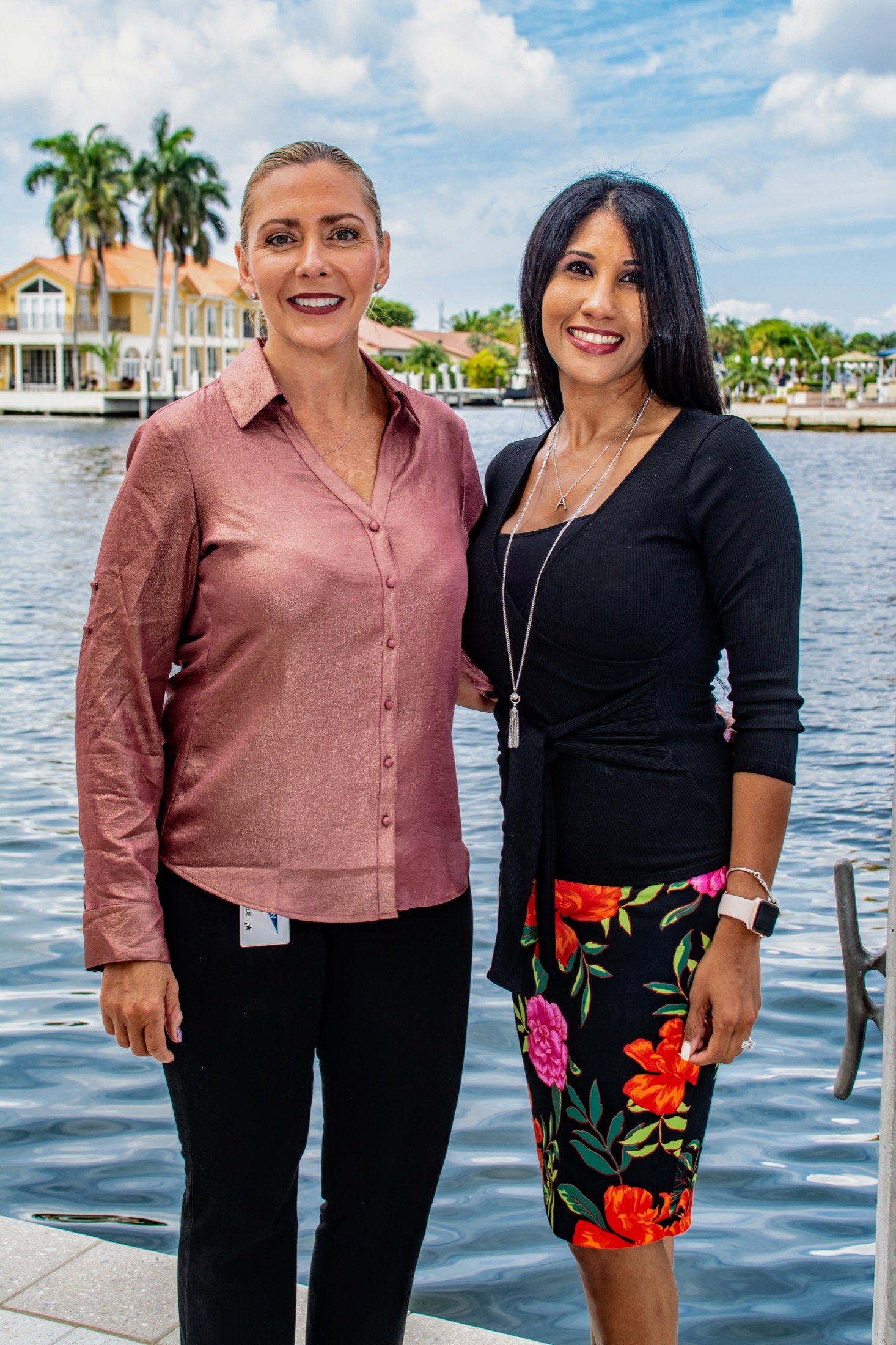 Two professionals posing together at a waterfront company gathering