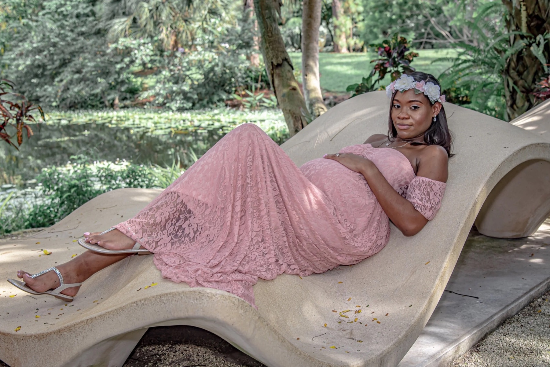 Expectant mother in a flowing blush maternity gown surrounded by South Florida greenery