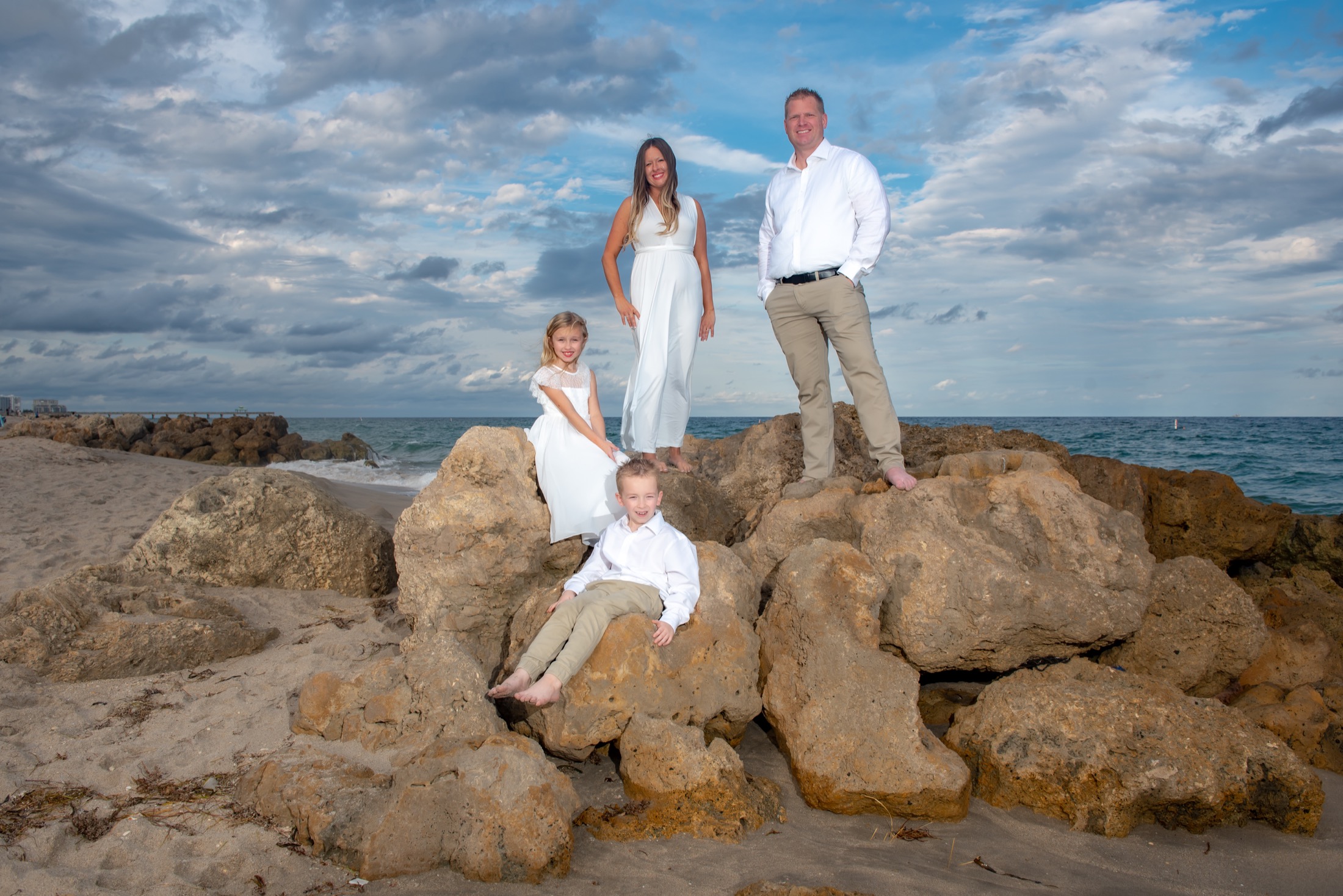 Family of four posed at different heights on beach rocks